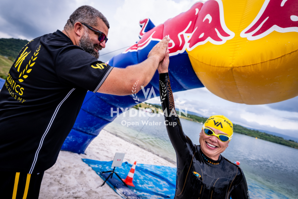 The head coach congratulates the swimmer after the HYDROMAN Most Swim race – high five, pride and success in open water swimming.
